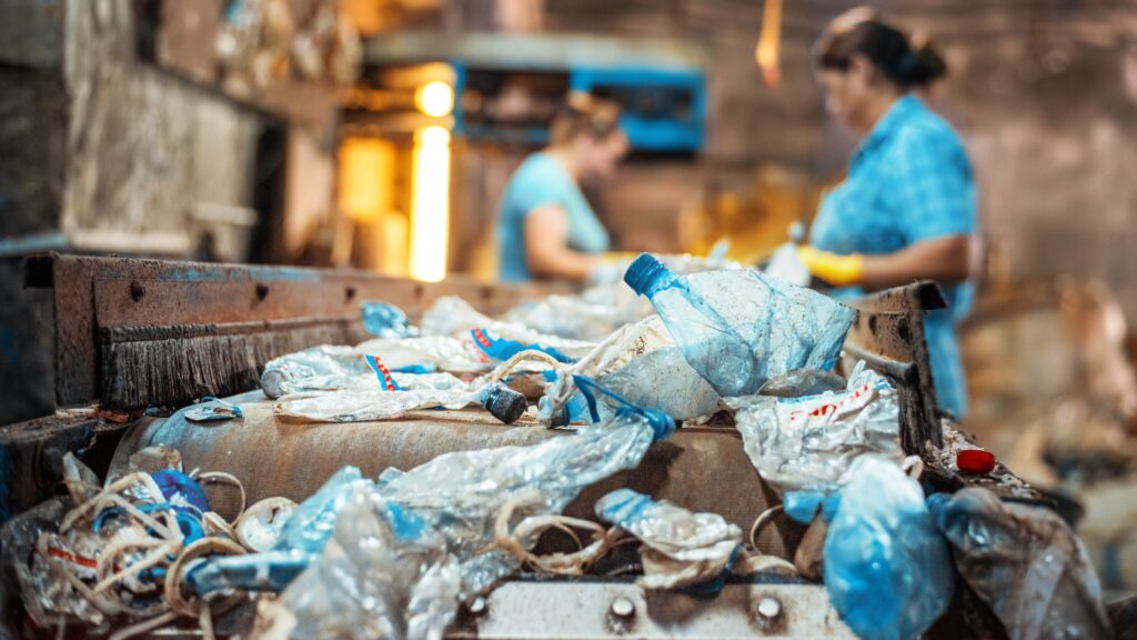 Workers in a plastics recycling factory inspecting sustainable materials and processing equipment