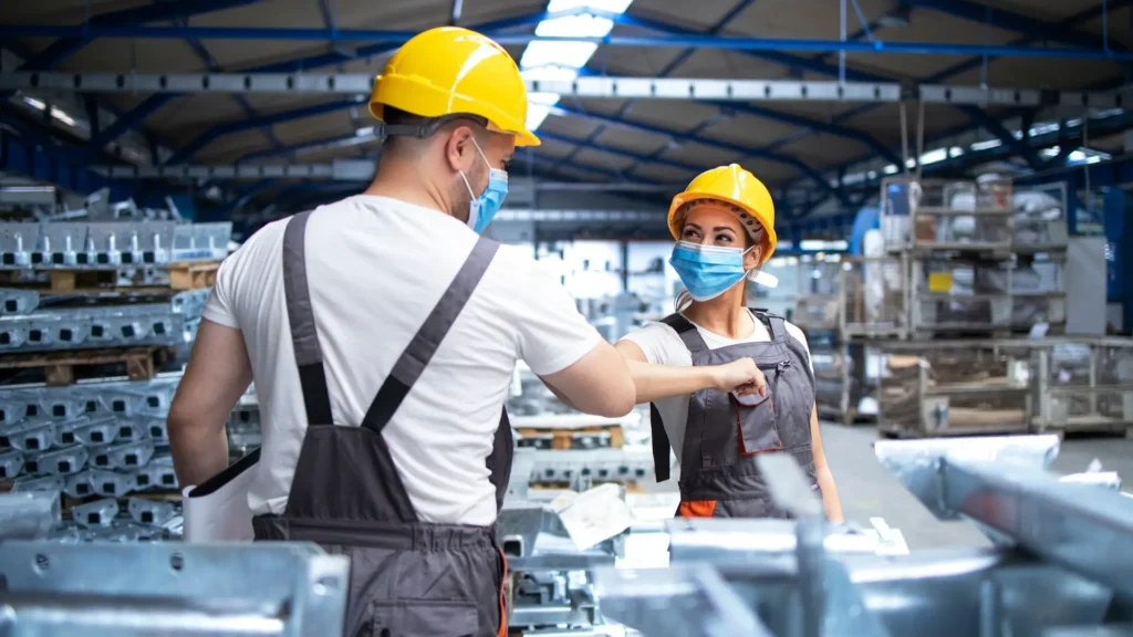 Manufacturing workers operating machinery in plastics production facility during industrial shift